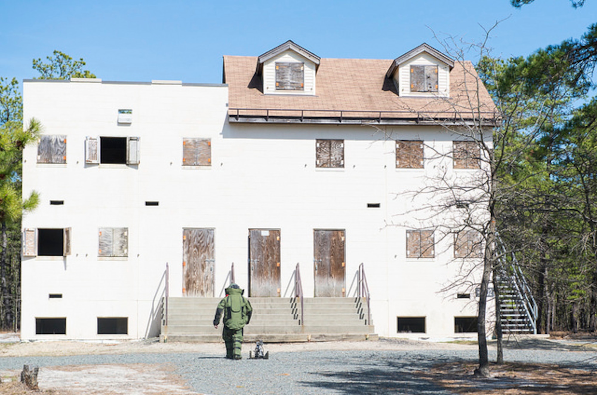 An explosive ordnance disposal technician approaches a building with a training improvised explosive device inside during Joint IED training on Joint Base McGuire-Dix-Lakehurst, N.J. March 30. Air Force and Marine Corps technicians from JB MDL, Dover Air Force Base, Delaware and Joint Base Langley-Eustis, Virginia participated in the training.