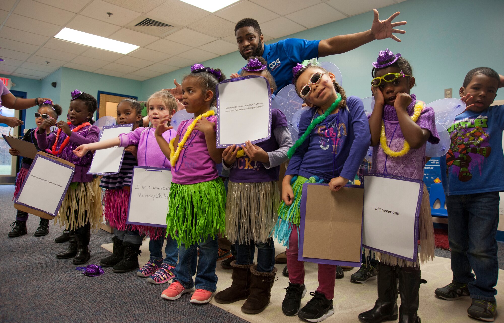 Terrell Dean, teacher’s assistant, and students celebrate the month of the military child at the Joint Base Andrews Child Development Center Three April 7, 2016. The students and faculty participated in a “purple” parade to kick of the month long celebration to honor military youth for the important role they play in contributing to the strength of the military family. The children wore placards that contained the Military Child’s Creed. (U.S. Air Force photo by Airman 1st Class Rustie Kramer/Released)