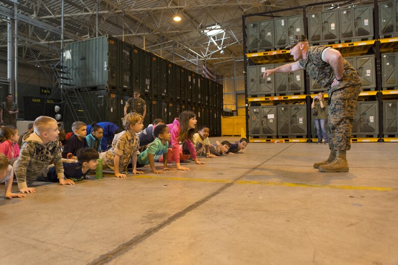 Cpl. Miguel Rivera, communication navigation technician with Marine Aviation Logistics Squadron 12, instructs children of service member’s assigned to Marine Aircraft Group 12 to do push-ups during Junior Recruit Day at Marine Corps Air Station Iwakuni, Japan, April 8, 2016. Junior Recruit Day allowed the children to get a first-hand look at what their military parent’s experiences on a daily basis. (U.S. Marine Corps photo by Sgt. Antonio J. Rubio)