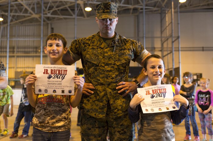 Cpl. Miguel Rivera, communication navigation technician with Marine Aviation Logistics Squadron 12, poses with Hayden Carr and Andrew Carr during their graduation of Junior Recruit Day at Marine Corps Air Station Iwakuni, Japan, April 8, 2016. Junior Recruit Day allowed children of service member’s assigned to Marine Aircraft Group 12 to get a first-hand look at what their military parents’ experiences on a daily basis. (U.S. Marine Corps photo by Sgt. Antonio J. Rubio)