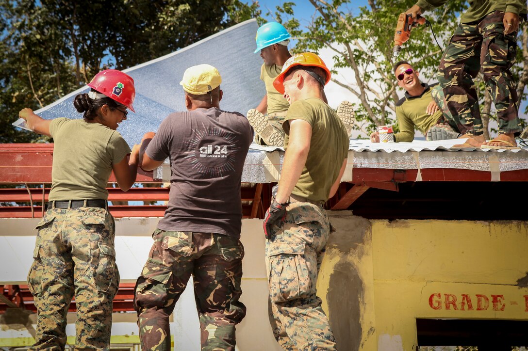 U.S. Marine Corps Cpl. Thelma Guerra, left, assigned to 9th Engineer Support Battalion, Philippine army soldier Pfc. Leo Genn Layson, assigned to 552 Engineer Construction Battalion and Lance Cpl. Matthew Hanks, assigned to 9th Engineer Support Battalion, work together to lay down aluminum during a Humanitarian Civic Assistant (HCA) project at Matangharon Elementary School in Iloilo, Philippines, as part of Exercise Balikatan 2016, April 9, 2016. The construction project is one of multiple HCAs taking place during this year's exercise, designed to improve the quality of life for the local populace and strengthen the bond between our two nations. Balikatan, which means "shoulder to shoulder" in Filipino, is an annual bilateral training exercise aimed at improving the ability of Philippine and U.S. military forces to work together during planning, contingency and humanitarian assistance and disaster relief operations. 
