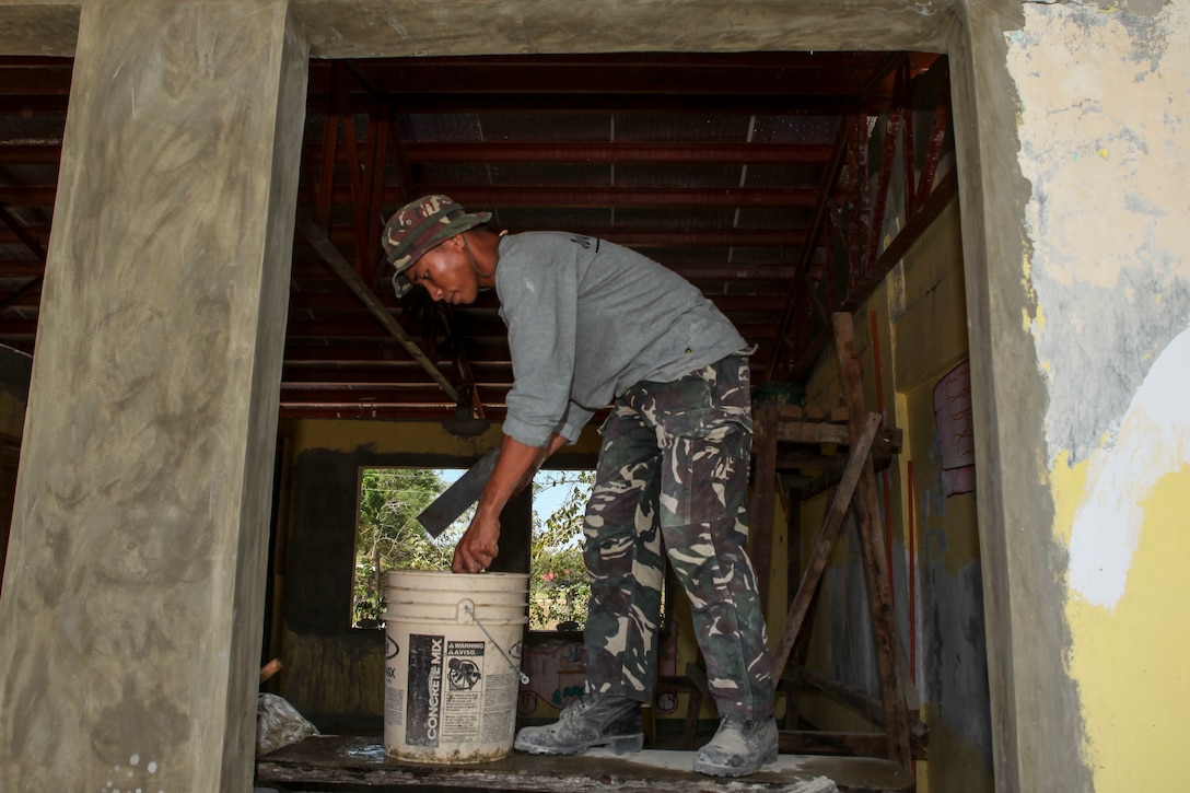 Philippine army soldier Cpl. Joey Canitan, engineer, assigned to the 552 Engineer Construction Battalion, flattens a layer of cement to help smooth the walls of a classroom at  Matangharon Elementary School during a Humanitarian Civic Assistant (HCA) project at Matangharon Elementary School in Iloilo, Philippines, as part of Exercise Balikatan 2016, April 9, 2016. The construction project is one of multiple HCAs taking place during this year's exercise, designed to improve the quality of life for the local populace and strengthen the bond between our two nations. Balikatan, which means "shoulder to shoulder" in Filipino, is an annual bilateral training exercise aimed at improving the ability of Philippine and U.S. military forces to work together during planning, contingency and humanitarian assistance and disaster relief operations. 