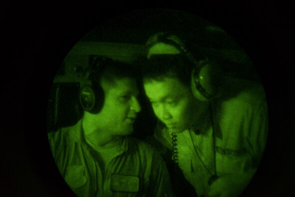 U.S. Air Force Capt. Andrew Kochman, 36th Airlift Squadron C-130 Hercules aircraft navigator, talks to a Philippine Air Force member from the 220th Airlift Wing April 7, 2016, during an Exercise Balikatan 2016 night flight over the Philippine Islands. PAF pilots and aircrew do not currently have night vision goggle capabilities, so the training given to them from members of the 36th AS was an entirely new experience. U.S. and Philippine military forces continually modernize and develop partner capabilities through bilateral exercises and subject matter expert exchanges. (U.S. Air Force photo by Staff Sgt. Michael Smith/Released)