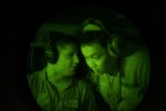 U.S. Air Force Capt. Andrew Kochman, 36th Airlift Squadron C-130 navigator, talks to a Philippine Air Force member from the 220th Airlift Wing during a night flight over the Philippine Islands, April 7, 2016. PAF pilots and aircrew do not currently have night vision goggle capabilities, so the training given to them from members of the 36th AS was an entirely new experience. (U.S. Air Force photo by Staff Sgt. Michael Smith/ Released)