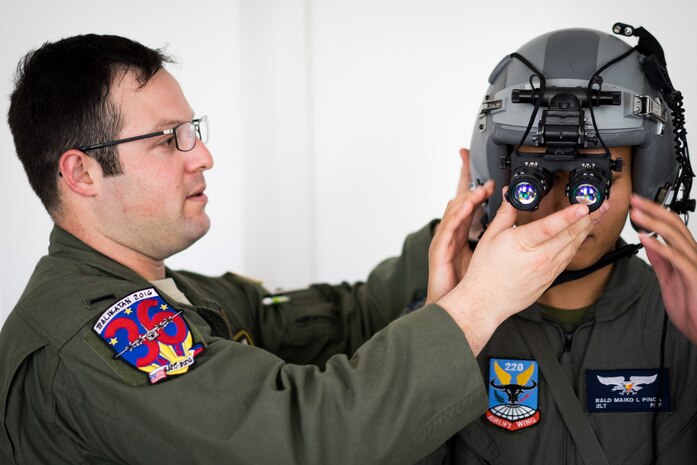 U.S. Air Force 1st Lt. Scott Brooks, 36th Airlift Squadron C-130 pilot, helps Philippine Air Force 2nd Lt. Rald Pinca, 220th Airlift Wing pilot, try on a flight helmet during an Exercise Balikatan training session on Mactan-Benito Ebuen Air Base, Philippines, April 7, 2016. Pilots and loadmasters from Yokota Air Base’s 36th AS shared their experiences of using night vision goggles and night flying during an all-day training session. (U.S. Air Force photo by Staff Sgt. Michael Smith/ Released)