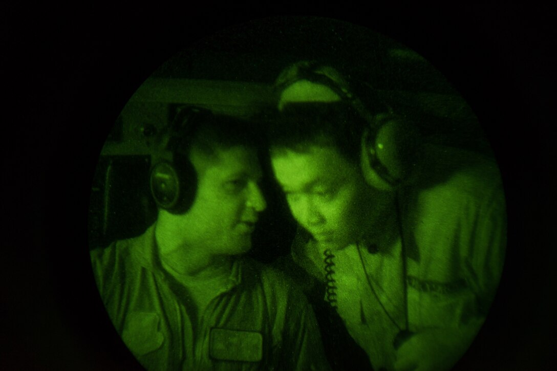 U.S. Air Force Capt. Andrew Kochman, 36th Airlift Squadron C-130 navigator, talks to a Philippine Air Force member from the 220th Airlift Wing during a night flight over the Philippine Islands, April 7, 2016. PAF pilots and aircrew do not currently have night vision goggle capabilities, so the training given to them from members of the 36th AS was an entirely new experience. (U.S. Air Force photo by Staff Sgt. Michael Smith/ Released)