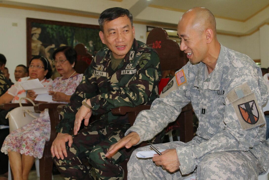 Brig. Gen. Dinoh A. Dolina, Armed Forces of the Philippines (AFP) assistant division commander, 3rd Infantry Division (left), and U.S. Army Reserve Cpt. Kevin K. Tran, 303rd Maneuver Enhancement Brigade, operations officer in charge in support of Balikatan 2016 Combined Joint Civil Military Operations Task Force, exchange military knowledge at Camp Peralta, Capiz, Philippines, while waiting to view a video memoir of the historical Bataan Death March of 1942, April 09, 2016. The viewing followed a flag raising ceremony. The ceremony was one of many that have brought together the AFP and U.S. military during the Balikatan 2016, “shoulder to shoulder”, exercise. Balikatan is an annual bilateral training exercise that allows for U.S. and Philippine forces to come together and train for potential real world events, better preparing them in supporting the local population. The ability of the AFP and U.S. military to work together, partner in capabilities and plan follow-on operations is essential to the relationship and interoperability of our forces. 