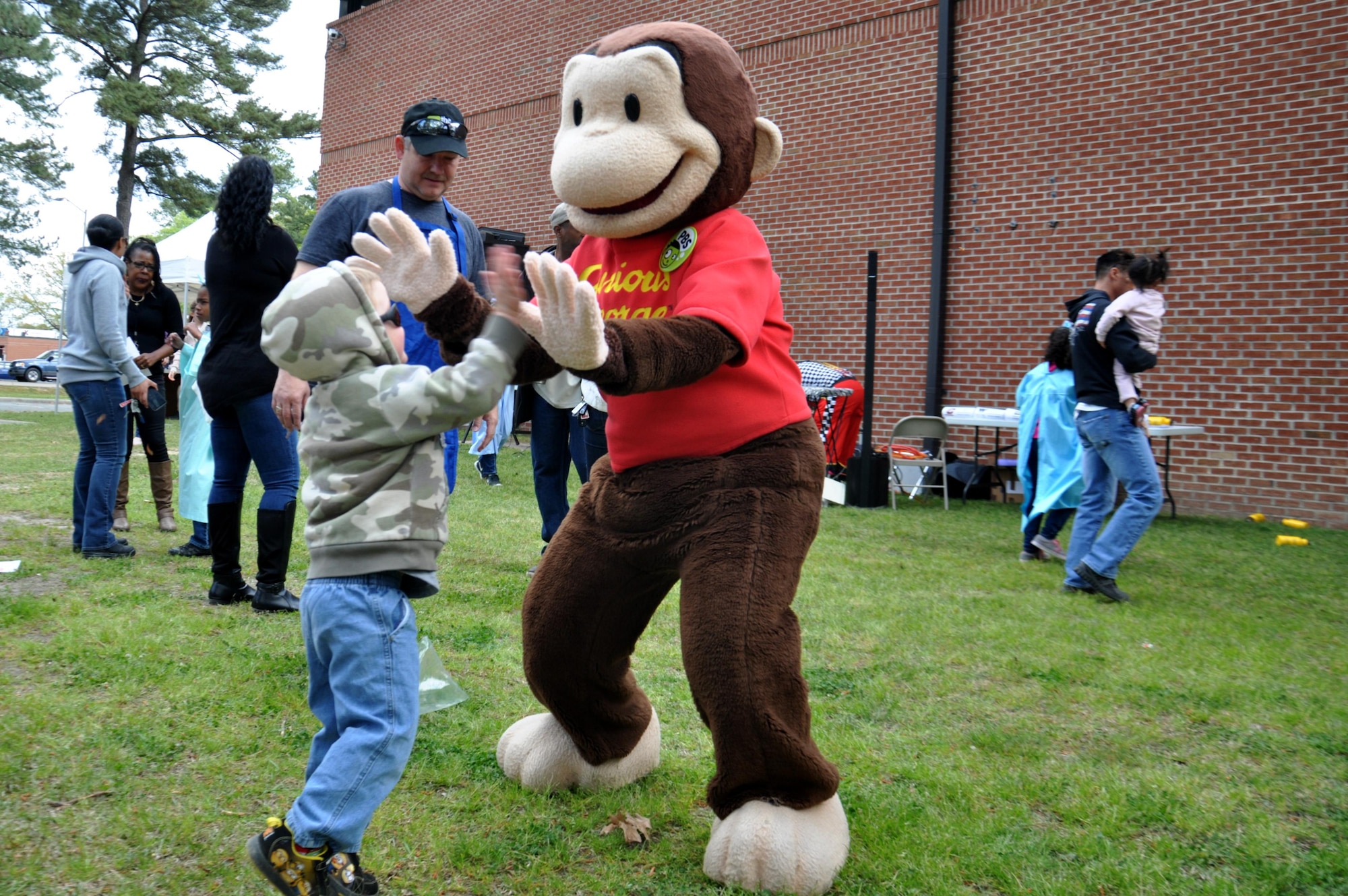 A member of Team Seymour high-fives Curious George during the Youth Center’s Month of the Military Child Carnival April 9, 2016, Seymour Johnson Air Force Base, North Carolina. Several characters were on hand to greet and take photos with attendees at the annual event. (U.S. Air Force photo/Staff Sgt. Chuck Broadway)