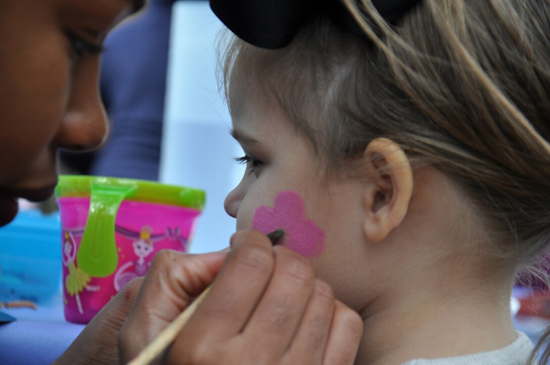 Airman 1st Class Laurie Acho, 4th Communications Squadron knowledge management technician, paints a flower on the face of the daughter of Airman 1st Class David Smetana, 4th Aircraft Maintenance Squadron avionics technician, April 9, 2016, at Seymour Johnson Air Force Base, North Carolina. Pony rides, a magic show and several other activities were available at the Month of the Military Child Carnival. (U.S. Air Force photo/Staff Sgt. Chuck Broadway)