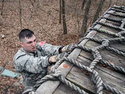 U.S. Army Reserve Sgt. Michael Mallett, 5th Battalion, 159th Aviation Regiment, 11th Theater Aviation Command, scales the cargo net of the Beaudoin Obstacle Course during the 2016 Joint Best Warrior Competition on Fort Knox, Kentucky, March 23, 2016. (U.S. Army Photo by Clinton Wood/Released)