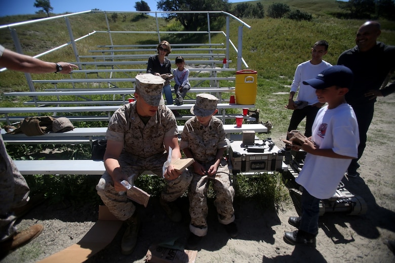 Nathan Aldaco, a 12 year-old boy with hypoplastic left heart syndrome, prepares to eat field rations with 1st Lt. Ernest Gaudio during a Make-A-Wish event supported by 7th Engineer Support Battalion, 1st Marine Logistics Group, aboard Camp Pendleton, Calif., March 24, 2016. Gaudio is a platoon commander with Bravo Company, 7th ESB, 1st MLG. Marines with 7th ESB and Explosive Ordnance Disposal helped to make Nathan’s wish of becoming a Marine come true by demonstrating the capabilities of their EOD robots and detonating TNT, C4, dynamite and blasting caps, while the heavy equipment operators gave him the opportunity to ride the D7 dozer and the excavator, in which he dug a pit, built a berm, and broke several large tree trunks.  (U.S. Marine Corps photo by Sgt. Laura Gauna/released)