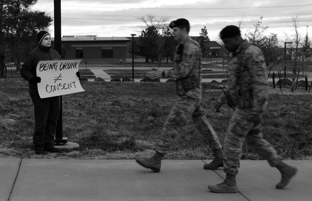 Eric Amaral, 28th Logistics Readiness Squadron inventory technician, displays a message as part of the Sexual Assault Awareness and Prevention Month kickoff event at Ellsworth Air Force Base, S.D., April 1, 2016. The all-black attire with white painted faces of participants in the “living display” symbolized the silence victims of sexual assault face while the signs promoted awareness. (U.S. Air Force photo by Airman 1st Class Denise M. Nevins/Released)