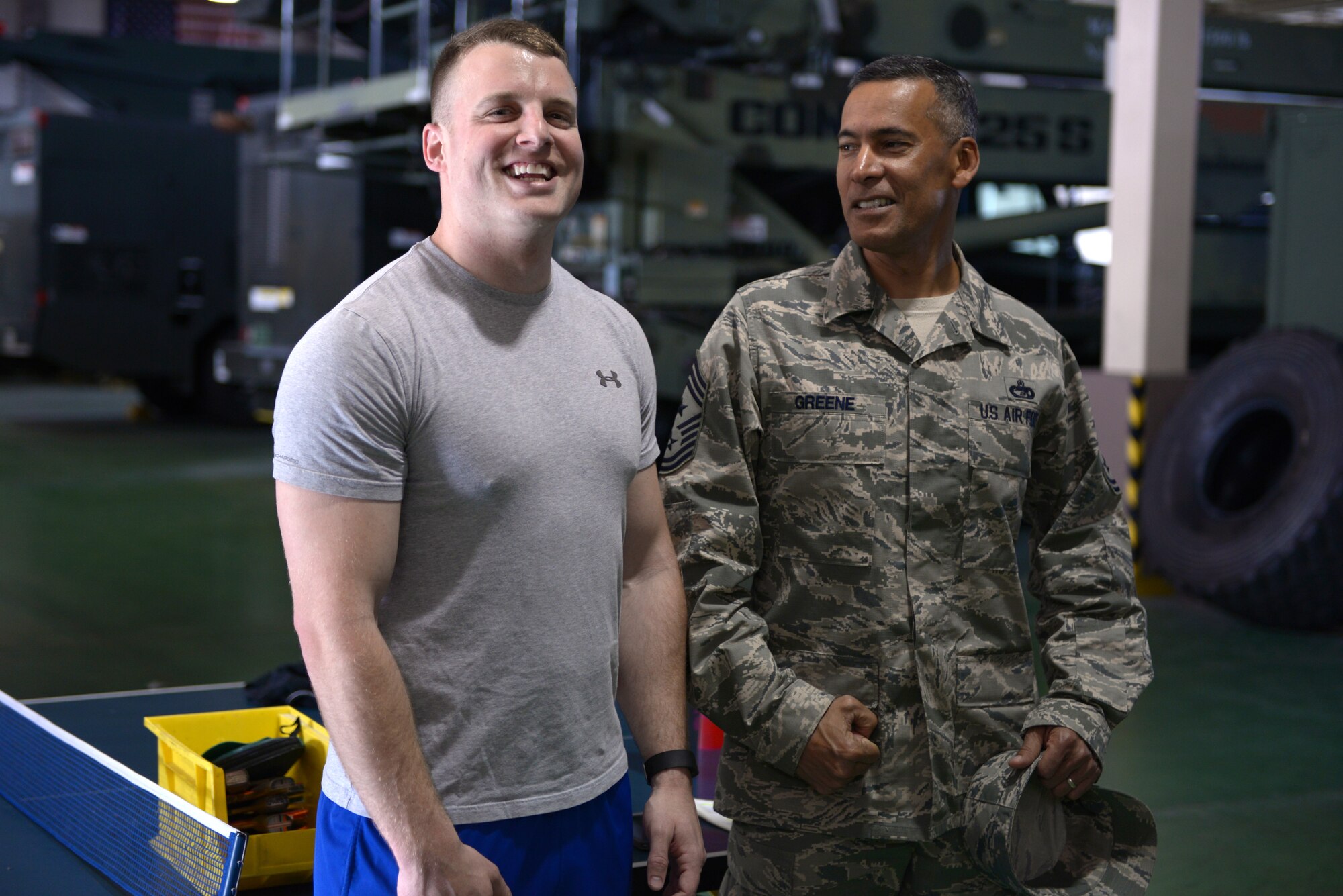 Chief Master Sgt. Terrence Greene (right), United States Forces, Japan and 5th Air Force command chief, flexes next to Staff Sgt. Scott Congdon, 730th Air Mobility Squadron crew chief, during his immersion tour at Yokota Air Base, Japan, April 6, 2016. Greene, the previous command chief for the 51st Fighter Wing at Osan Air Base, Korea, is new to the position and used his tour to meet Airman at facilities across his new home installation. (U.S. Air Force photo by Staff Sgt. Cody H. Ramirez/Released)