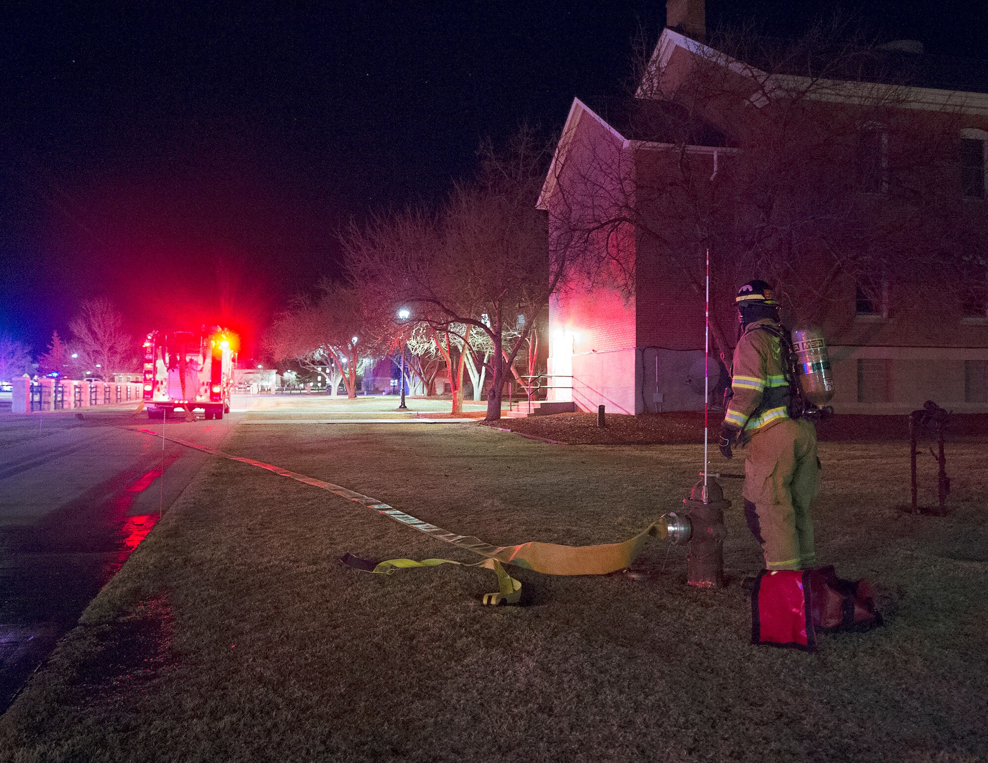 A firefighter with the F.E. Warren Air Force Base, Wyo., Fire Department lay hose from a hydrant to their truck March 9, 2016, as they respond to a fire alarm in the 90th Missile Wing headquarters building. (U.S. Air Force photo by R.J. Oriez)