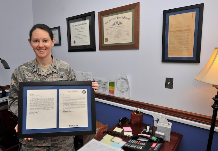 Capt. Lindsey Callahan, the deputy staff judge advocate with the 70th Intelligence, Surveillance, and Reconnaissance Wing at Fort George G. Meade, Md., poses with a letter of reprimand her father received when he was in the Air Force in the 1960s. As deputy staff judge advocate, she assists the staff judge advocate to deliver comprehensive legal services to the Wing, including directing military justice, civil law, claims, legal assistance and preventive law programs. 
 (U.S. Air Force photo/Staff Sgt. AJ Hyatt)
