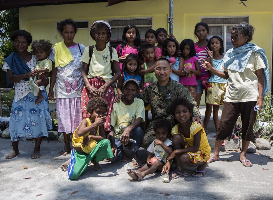 U.S. sailor Hospital Corpsman 1st Class Jose G. Esguerra poses for a photo with Philippine families from Maruglo Elementary School, at Crow Valley, Philippines, April 7, 2016. Esguerra is a dental technician with 3rd Dental Battalion, 11th Dental Regiment, currently attached to 3rd Medical Battalion, 3rd Marine Division, III Marine Expeditionary Force. Esguerra has been in the Navy for 17 years and for the first time, returned home to give back to his country. (U.S. Photo by Lance Cpl. Jessica N. Etheridge/Released)