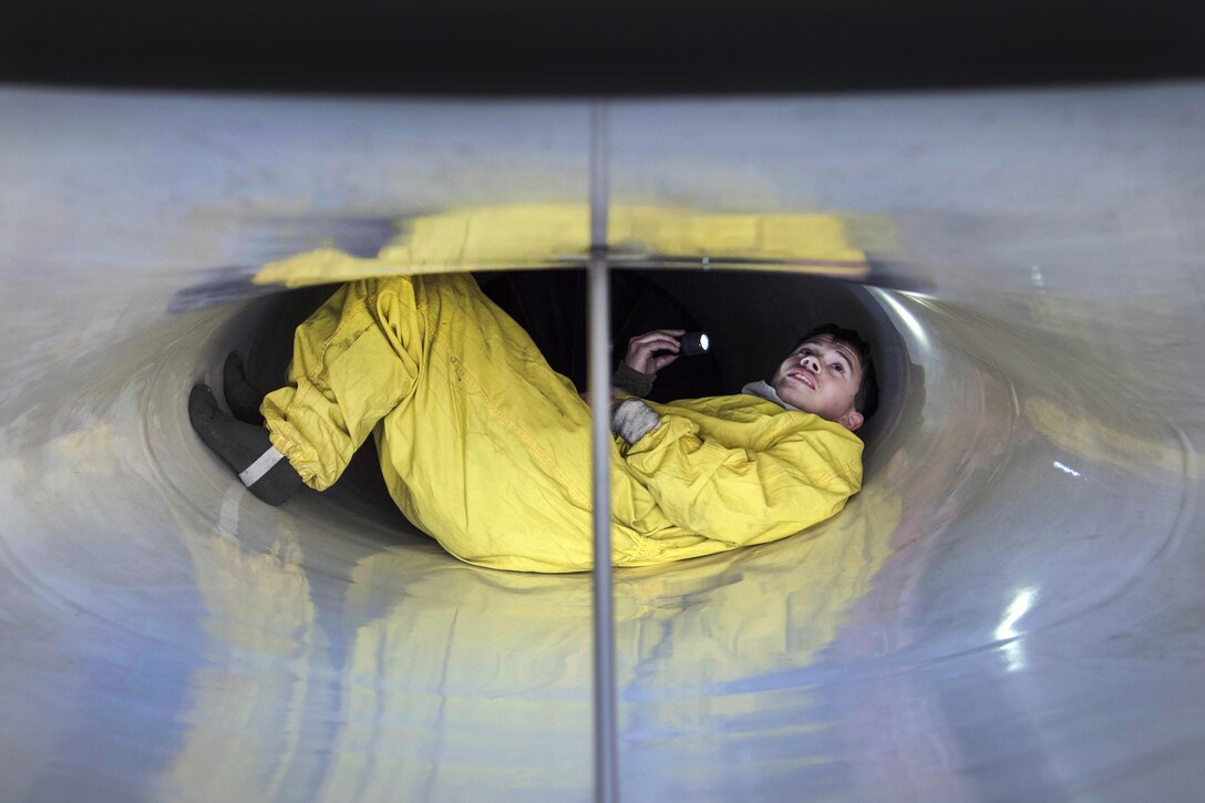 Air Force Senior Airman Bradley Poirier inspects the intake of an F-16 Fighting Falcon aircraft during a two-day surge exercise at Misawa Air base, Japan, April 5, 2016. Poirier is a crew chief assigned to the 35th Maintenance Squadron. Protective suits are worn to increase maneuverability and prevent damage to the intake. Air Force photo by Airman 1st Class Jordyn Fetter