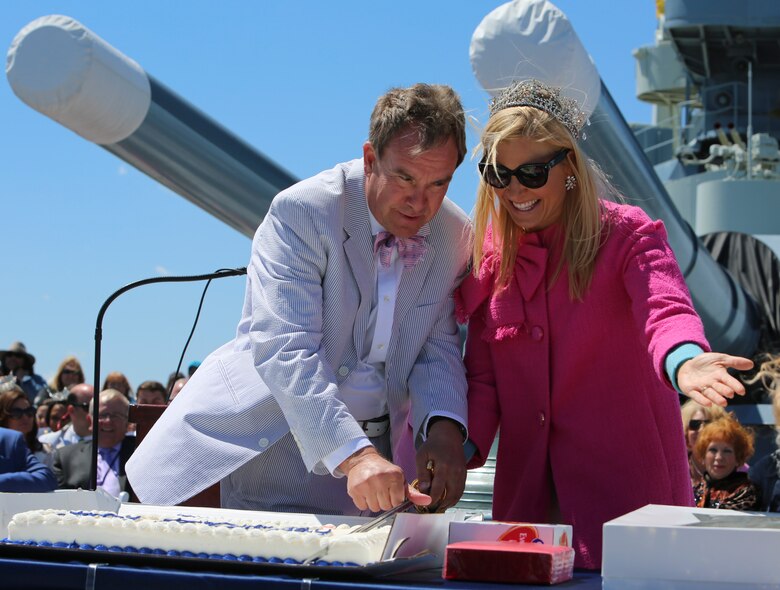 The ceremony announcer and Anna Kooiman, Queen of the Azalea Festival, cuts a ceremonial cake with the naval officer’s sword to kick-start the 75th anniversary celebration of the commissioning of the USS North Carolina (BB-52) Battleship in Wilmington, N.C., April 9, 2016. Miss North Carolina, Kate Peacock, and the rest of the Azalea Festival court also attended the ceremony. (U.S. Marine Corps photo by LCpl. Miranda Faughn/Released)
