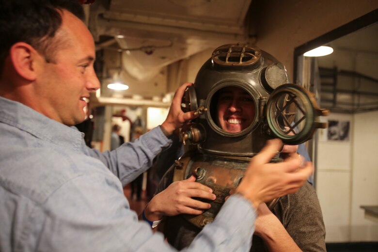 Petty Officer 1st Class Christopher Burns, a reconnaissance Navy diver, helps a visitor to the USS North Carolina (BB-52) Battleship Memorial try on a dive suit helmet during the celebration of the ship’s 75th anniversary of its commissioning in Wilmington, N.C., April 9, 2016. Guests of the celebration saw historical artifacts and role-playing of Marines and sailors from 2nd Tank Battalion and other 2nd Marine Division units as they showcased how different parts of the ship operated. (U.S. Marine Corps photo by LCpl. Miranda Faughn/Released)