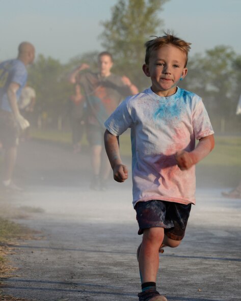 A child runs in the Helping Agency 5K on Barksdale Air Force Base, La., April 8, 2016. The white chalk represented chaplain and comprehensive Airmen fitness. Other colors including teal, red and orange, represented additional helping agencies taking part in the 5K event. (U.S. Air Force photo/Senior Airman Jannelle Dickey)
