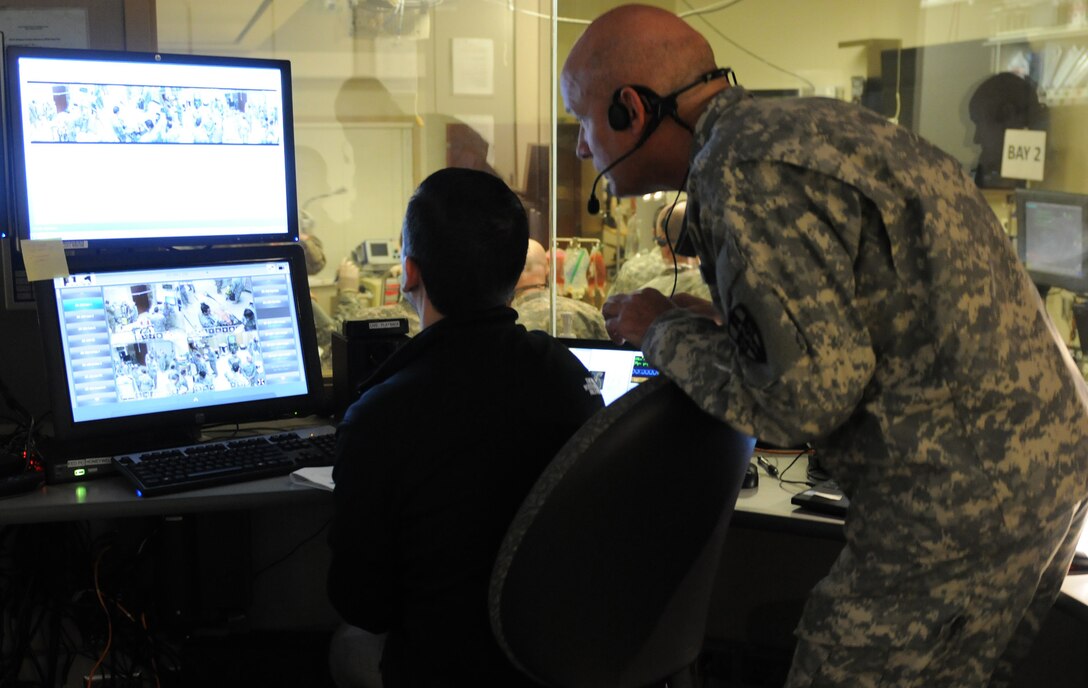 An observer-controller/trainer with the Medical Readiness and Training Command, Army Reserve Medical Command, and a simulation technician with the Mayo Clinic, observe as Soldiers from the 399th Combat Support Hospital, 804th Medical Brigade, 3d Medical Command (Deployment Support) as they conduct an exercise April 2, 2016 at the Mayo Clinic Multidisciplinary Simulation Center in Rochester, Minnesota. The state-of-the-art equipment at the facility gave the OC/Ts a bird's eye view of the Soldiers conducting the exercise and also allowed them to manipulate the scenarios by remotely changing patient vital signs.