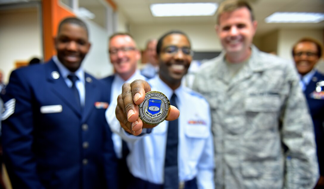 Senior Airman Vincent Lang, 932nd Medical Squadron public health technician, is presented with a chief's coin from newly appointed 932nd Airlift Wing command chief, Chief Master Sgt. Chad Welch, during a surprise gathering by fellow MDS Airmen April 3, 2016, Scott Air Force Base, Illinois.  Lang was recognized for his job performance, can do attitude and volunteer efforts within the Wing.  (U.S. Air Force photo by Tech. Sgt. Christopher Parr)
