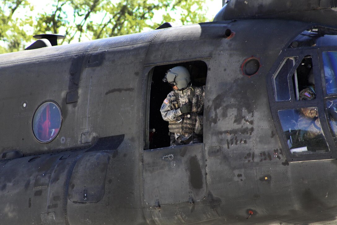 A soldier checks for clearance before taking off in a CH-47D Chinook helicopter during slingload training at Clarks Hill Training Site at Plum Branch, South Carolina, April 2, 2016. South Carolina Army National Guard photo by Capt. Brian Hare