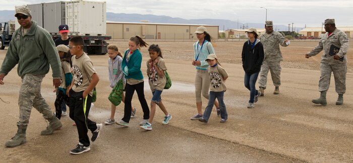 An Airman from Holloman’s Basic Expeditionary Airfield Resources (BEAR) Base leads a group of children to the next station during Operation K.I.D. (Kids Investigating Deployment), April 8 at Holloman Air Force Base, N.M. April is the Month of the Military Child. The Airmen and Family Readiness Center and Youth Center hosted Operation K.I.D. to expose military children to the different phases of deployment that their active duty family members go through.