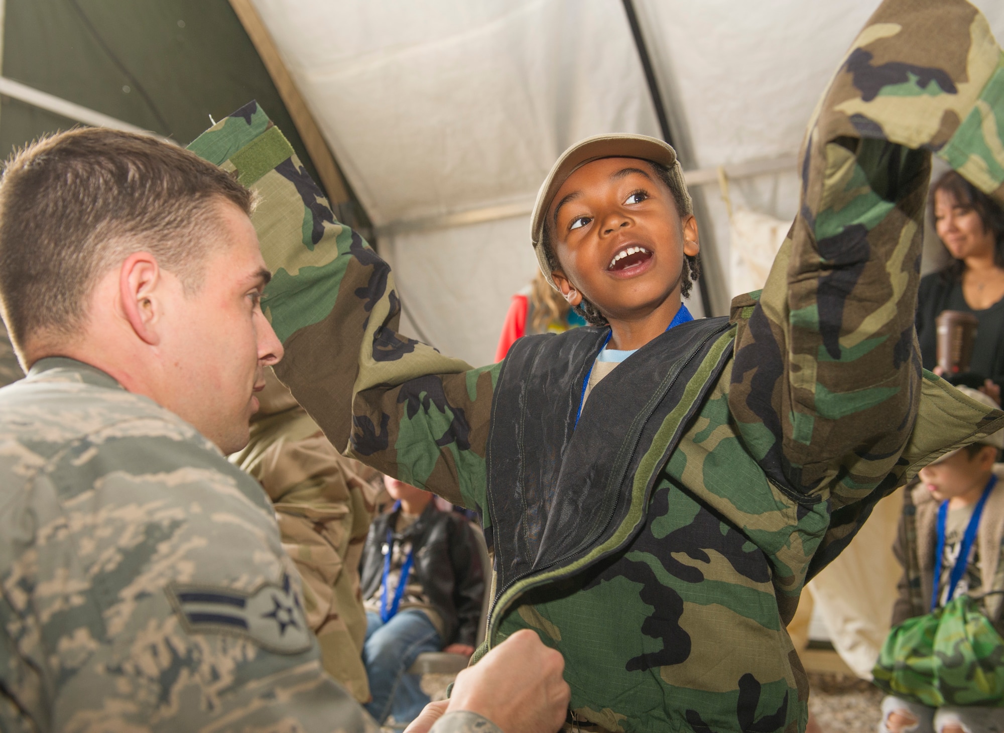 Airman 1st Class Patrick O’Donnell, a 49th Civil Engineer Squadron specialist, assists Antonio Jones, 5, with putting on personal chemical protective gear during Operation K.I.D. (Kids Investigating Deployment), April 8 at Holloman Air Force Base, N.M. April is the Month of the Military Child. The Airmen and Family Readiness Center and Youth Center hosted Operation K.I.D. to expose military children to the different phases of deployment that their active duty family members go through.