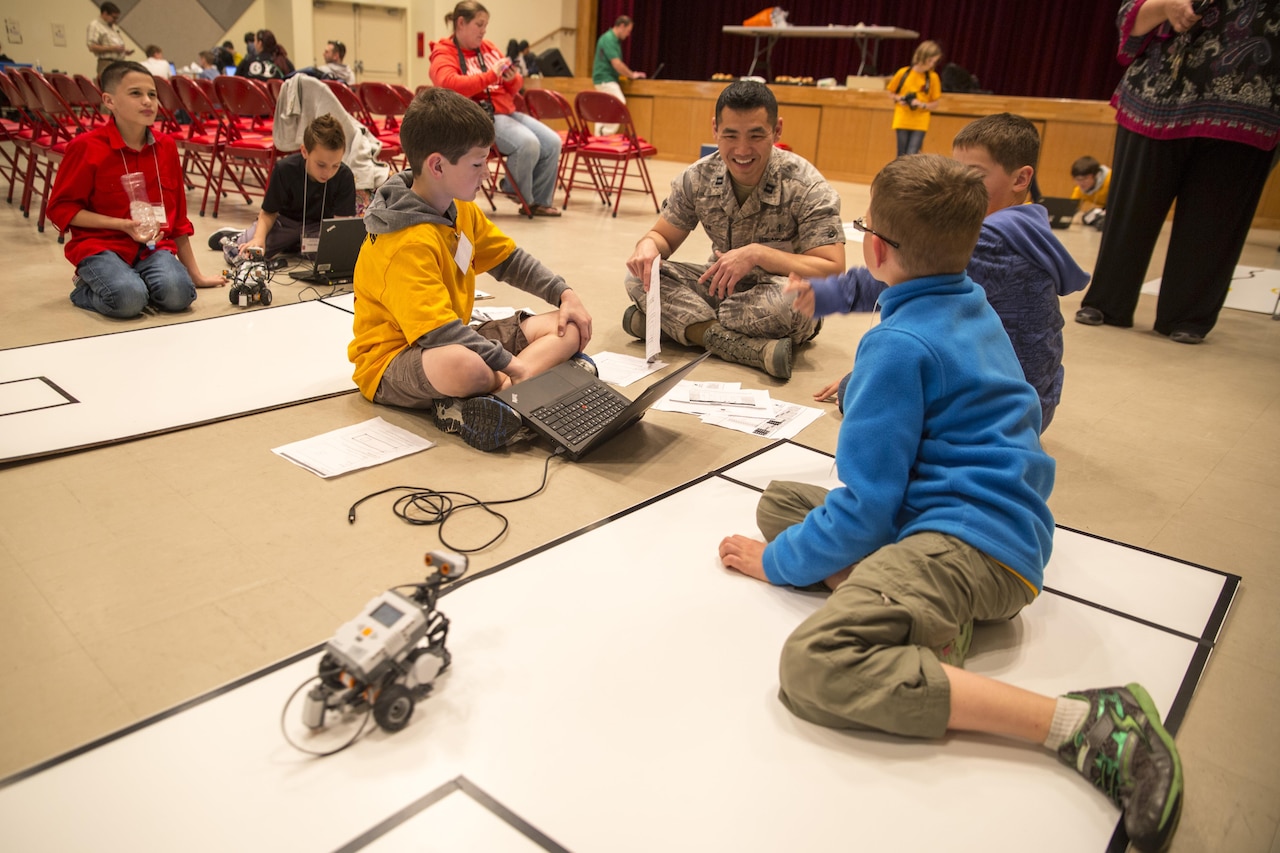 Air Force Capt. Michael K. Kan, center right, a bioenvironmental engineer, talks with robotics club students at the Camp Foster Community Center at Okinawa, Japan, Feb. 20, 2014, during the first robotics competition sponsored by Department of Defense Education Activity Okinawa District. Marine Corps photo by Cpl. Joey Holeman