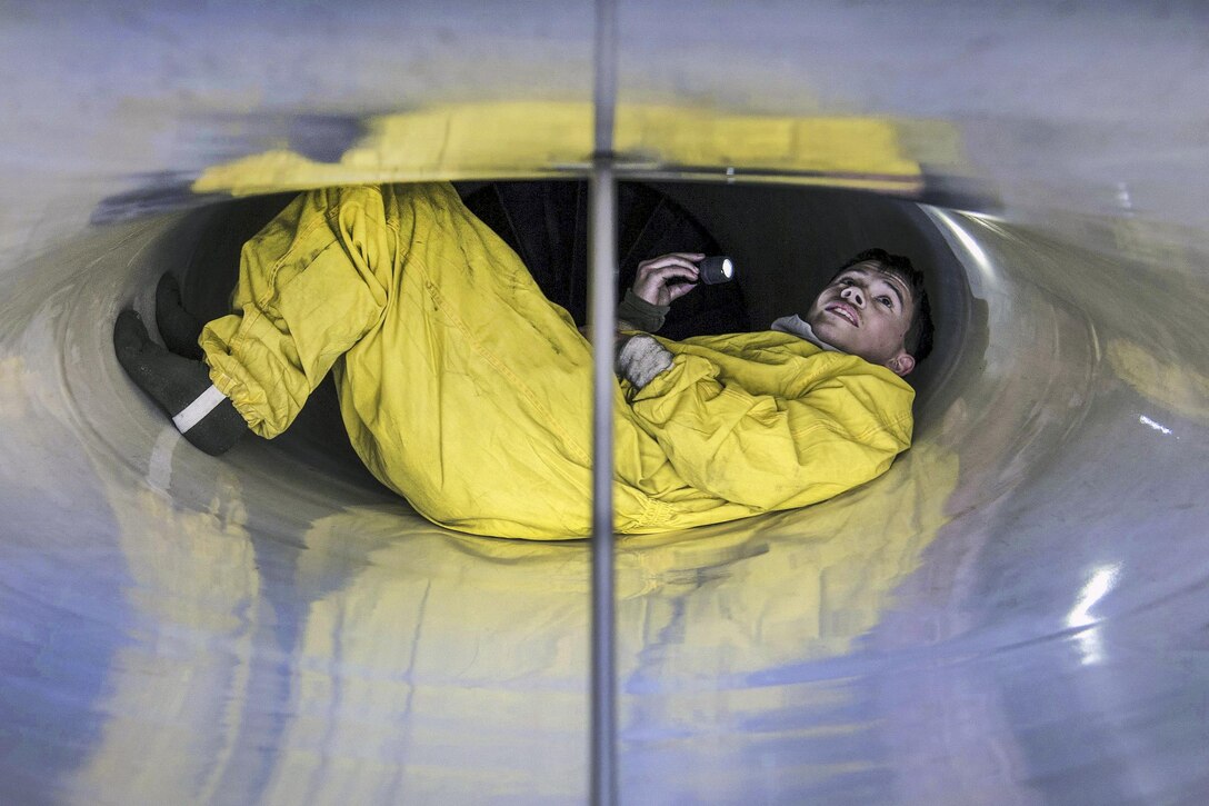 Air Force Senior Airman Bradley Poirier inspects the intake of an F-16 Fighting Falcon aircraft during a two-day exercise at Misawa Air Base, Japan, April 5, 2016. Poirier is a crew chief assigned to the 35th Maintenance Squadron. Airmen wear protective suits to increase maneuverability and prevent damage to the intake. Air Force photo by Airman 1st Class Jordyn Fetter