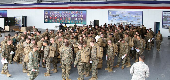 U.S. Marines from the III Marine Expeditionary Force, fall in line to in-process to the Joint Reception Center, April 2, at Clark Air Base in Angeles City, Philippines. The JRC is the first stop of the trip for U.S. military personnel entering the country where they go through immigration and customs.