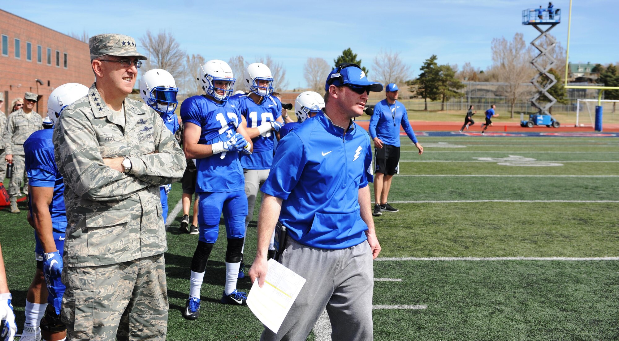 Gen. John Hyten, commander of U.S. Air Force Space Command at Peterson Air Force Base, and Falcons Football offensive coordinator Mike Thiessen, watch a play they called on the sidelines during the spring scrimmage at Fountain-Fort Carson High School, April 9, 2016. Hyten served as Air Force's head coach during the hour-long scrimmage. (U.S. Air Force photo/John Van Winkle)