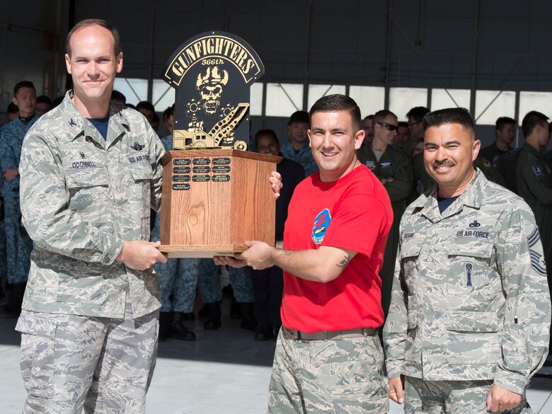 366th Fighter Wing Commander Col. Jefferson O'Donnell and Wing Weapons Manager Chief Master Sgt. Patrick Sebay recognize Senior Airman Mariao Estrada, 389th Aircraft Maintenance Unit weapons load crew member, as the winner of a maneuverability competition with bomb loaders April 9, 2016, at Mountain Home Air Force Base, Idaho. The 389th AMU and the 428th AMU competed in the maneuverability test which consisted of driving a MJ-1C 82 bomb loader through a course carrying an object to a chosen destination. (U.S. Air Force photo by Chester Mientkiewicz/Released)
