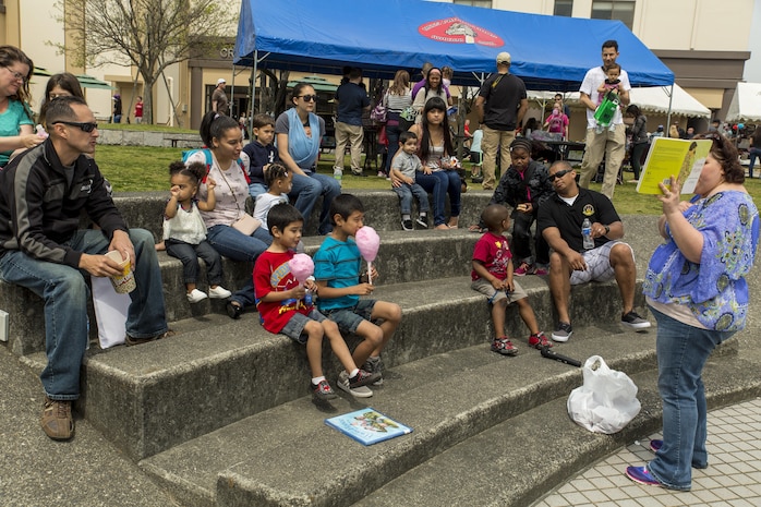 Tonya Van Winkle, training curriculum specialist with the Family Care Branch, reads “Home Again” by Dorinda Silver Williams, during the 13th annual Month of the Military Child festival at Marine Corps Air Station Iwakuni, Japan, April 9, 2016. The month of April honors and recognizes military children for the struggles they overcome such as frequent moves, school changes and separation from active duty parents. The festival also offered children the opportunity to play games, get their faces painted, draw, dance, participate in a raffle and have story time. (U.S. Marine Corps photo by Lance Cpl. Aaron Henson/Released)