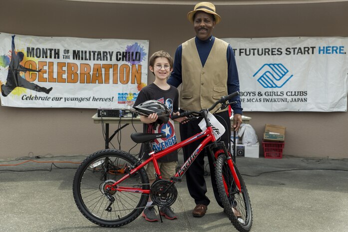 Adam Boardman, a third grader at Matthew C. Perry Elementary School, poses for a photo with Eugene Clark, Youth and Teen Center director, after winning a bike in a raffle during the 13th annual Month of the Military Child festival at Marine Corps Air Station Iwakuni, Japan, April 9, 2016. The month of April honors and recognizes military children for the struggles they overcome such as frequent moves, school changes and separation from active duty parents. (U.S. Marine Corps photo by Lance Cpl. Aaron Henson/Released)