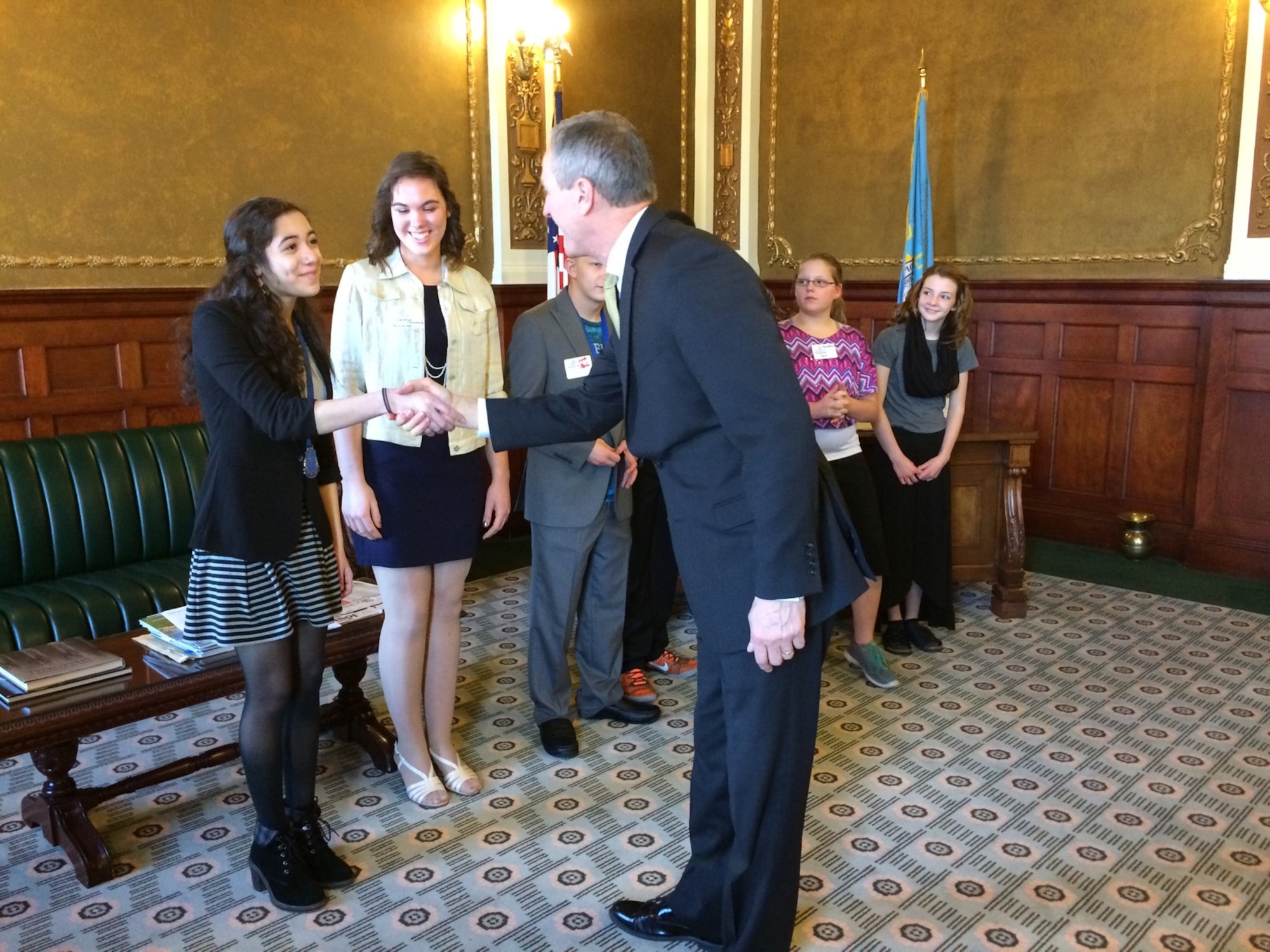 Ria Gualano, daughter of Lan Gualano, 28th Comptroller Squadron quality assurance manager, shakes hands with Dennis Daugaard, South Dakota governor, at Box Elder, S.D., March 21, 2016. The Military Youth of the Year competition is a part of Boys & Girls Clubs of the America's premier youth recognition program for members who promote service to the Club, community, and family; as well as good academic performance, moral character, life goals, poise and public speaking ability. (Courtesy photo by Lan Gualano/Released)