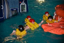 Members of the Lilac Festival Royalty Court swim to a life raft during a water survival demonstration April 11, 2016, at Fairchild Air Force Base, Wash. During the water survival demonstration, the princesses joined the SERE instructors in the pool. While in the pool, they learned how to escape a mock downed aircraft, known as the Modular Egress Training System, how to get to the life raft and how to survive in it. (U.S. Air Force Photo/Airman 1st Class Taylor Bourgeous)