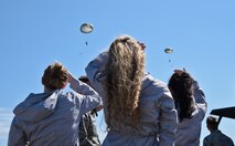 Lilac princesses watch as two members from the 336th Training group parachute down during a demonstration April 11, 2016, at Fairchild Air Force Base, Wash. During their visit, the Princesses observed a SERE water survival demonstration, learned basic water survival skills and watched a parachute jump demonstration. (U.S. Air Force Photo/Airman 1st Class Taylor Bourgeous)