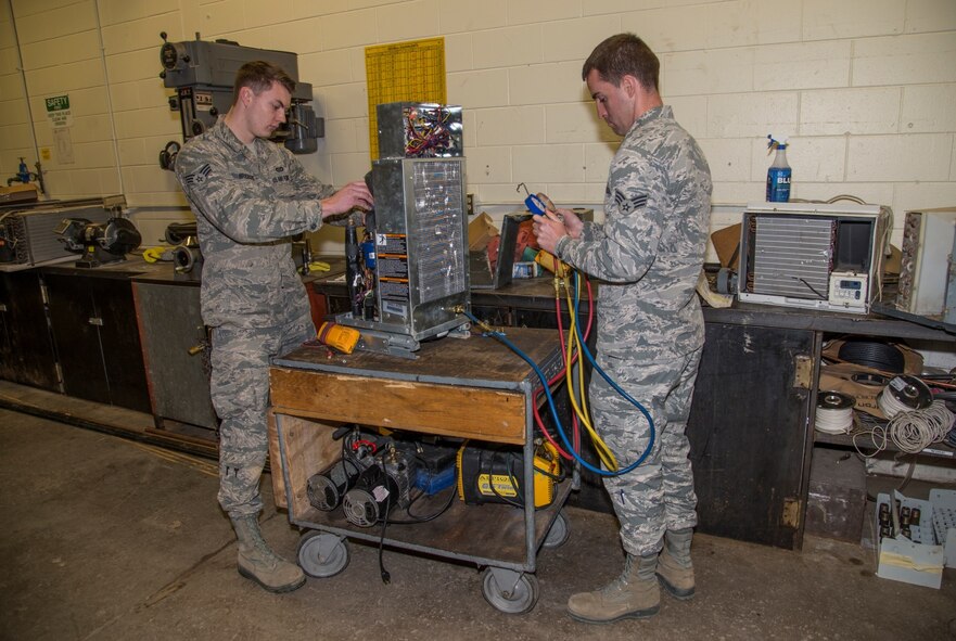 Senior Airman Mark Brisbois and Senior Airman Michael Robinson, 5th Civil Engineer Squadron heating, ventilation and air conditioning journeymen, work on a geothermal heat pump at Minot Air Force Base, N.D., April 5, 2016. HVAC repairs and replaces the heating and cooling units, among other things, for the squadrons on base. (U.S. Air Force photo/Airman 1st Class Christian Sullivan)