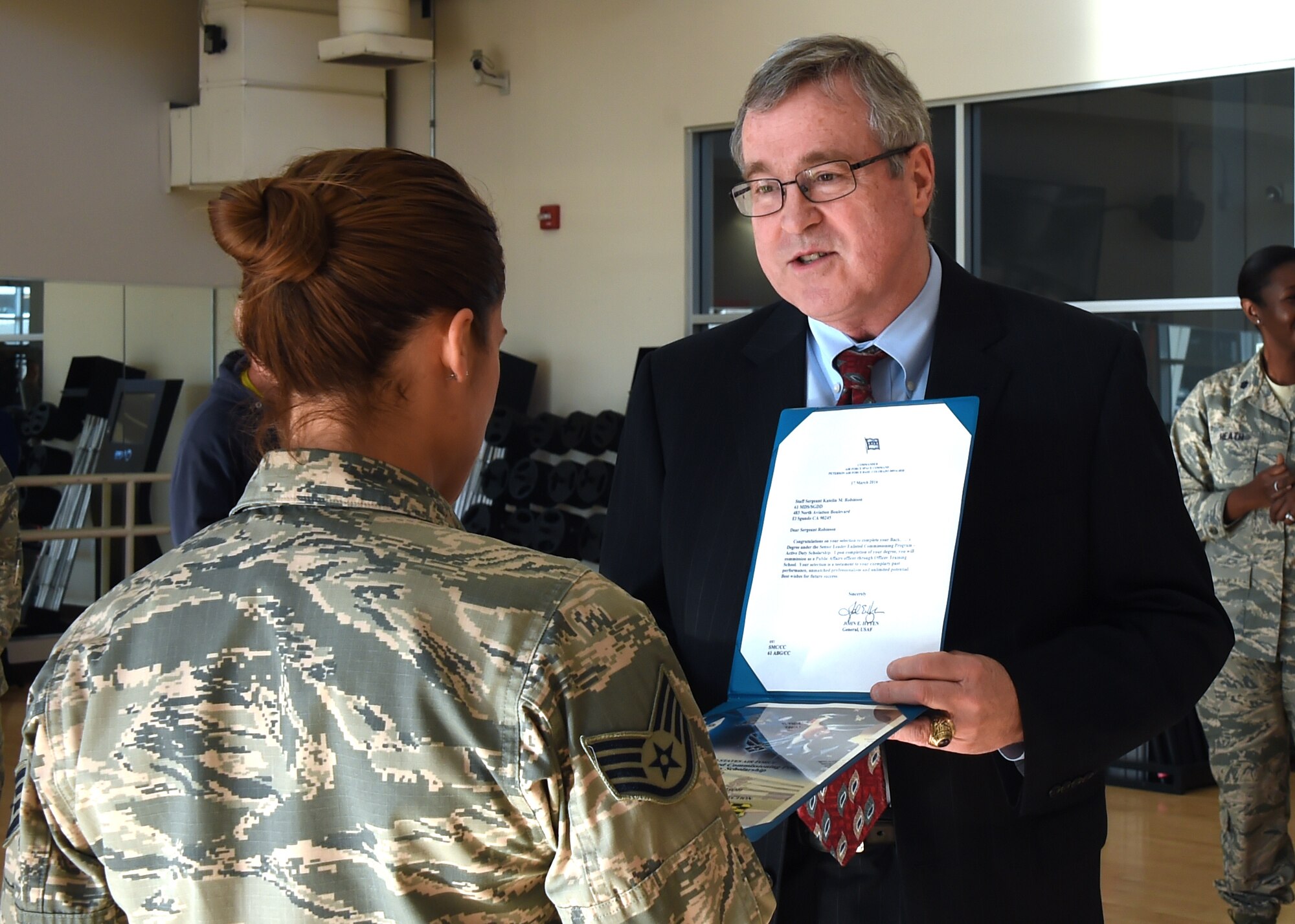 Thomas Fitzgerald, Space and Missile Systems Center acting executive director, presents a certificate and letter of selection for Officer Training School through the Senior Leader Enlisted Commissioning Program from Gen. John Hyten, commander of Air Force Space Command to Staff Sgt. Katelin Robinson, 61st Medical Squadron noncommissioned officer in charge of Dental Logistics at the Los Angeles Air Force Base medical clinic in El Segundo, Calif. (U.S. Air Force photo/Sarah Corrice)