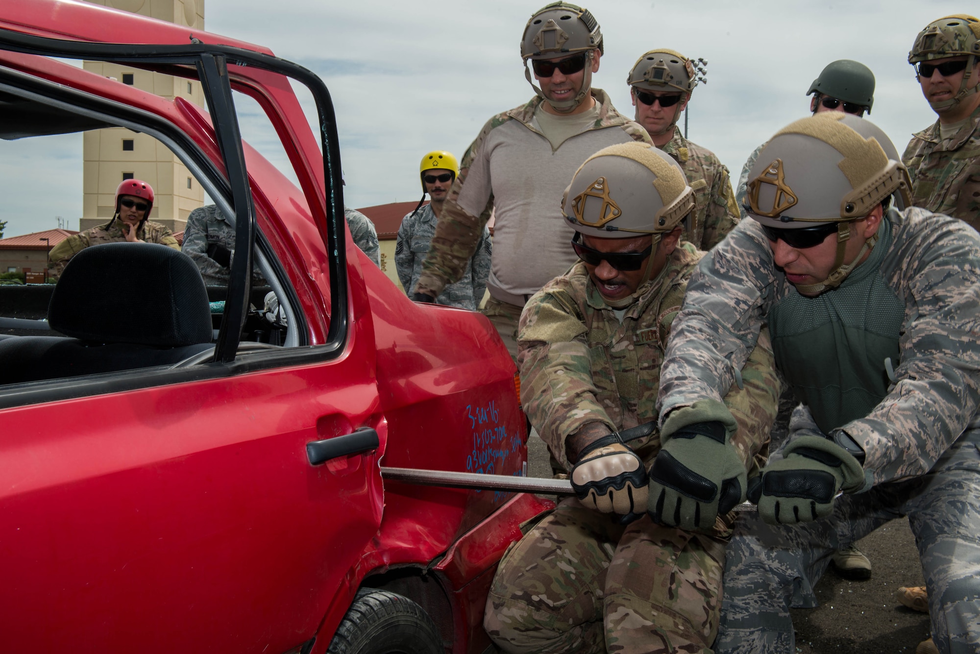 Staff Sgt. Angel Moquete, left, and Master Sgt. Edgar Gonzalez both 571st Mobility Support Advisory Squadron, work to open a car door during vehicle extrication training April 7, 2016, at Travis Air Force Base, California. The Team Travis fire department worked with the 571st Mobility Support Advisory Squadron on vehicle extrication for future deployments to South and Central America. (U.S. Air Force photo by Staff  Sgt. Robert  Hicks/Released)   