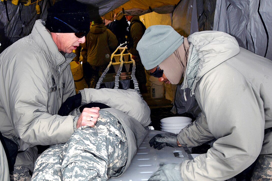 Army Spc. Benjamin Footman, right, helps a simulated patient during Exercise Arctic Eagle 2016 at Camp Grayling, Mich., April 5, 2016. Footman is assigned to the Indiana Air National Guard’s 438th Chemical Company. Air Force photo by Master Sgt. David Kujawa