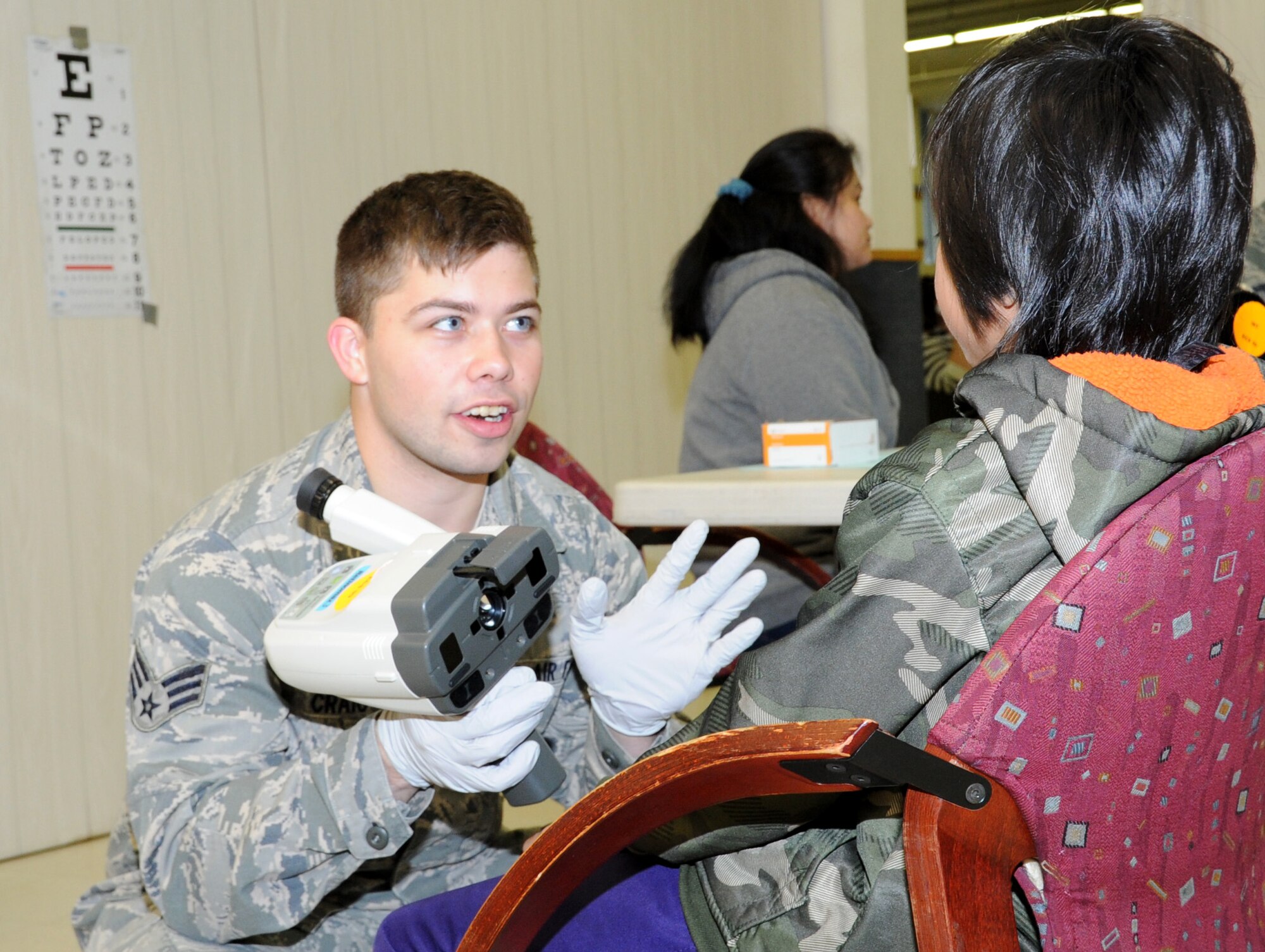 Senior Airman Jesse Craig, an ophthalmic technician assigned to the 910th Medical Squadron at Youngstown Air Reserve Station, Ohio, talks to a young patient during Arctic Care 2016 in Kodiak, Alaska. (U.S. Air Force photo by Bo Joyner)
