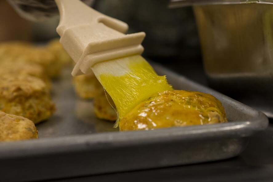A U.S. Air Force Airman from the 23d Force Support Squadron, butters the top of a biscuit, April 7, 2016, at Moody Air Force Base, Ga. The 23d Force Support Squadron deploys food specialists worldwide to ensure Airmen are fueled and ready to complete the mission. (U.S. Air Force photo by Airman Daniel Snider/Released)