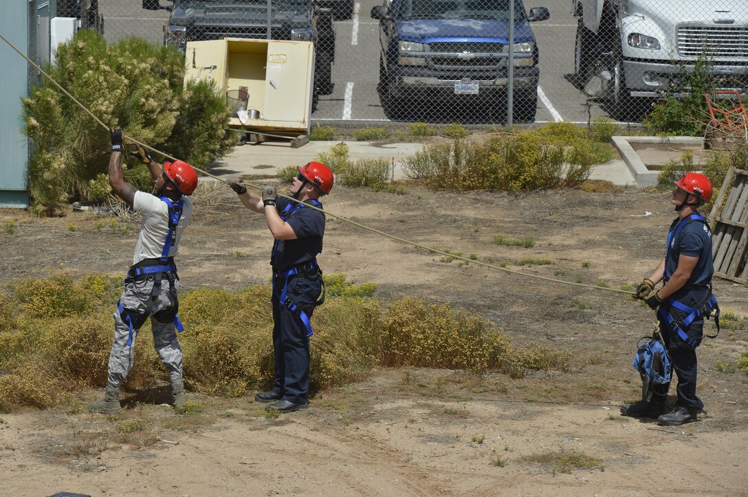 A team of firefighters from Luke and Davis-Monthan Air Force Bases Civil Engineer Squadrons control the descent of a training mannequin being lowered from the top of the water tower during a rappelling exercise April 8, 2016, at Luke AFB, Ariz. (U.S. Air Force photo by Senior Airman James Hensley)