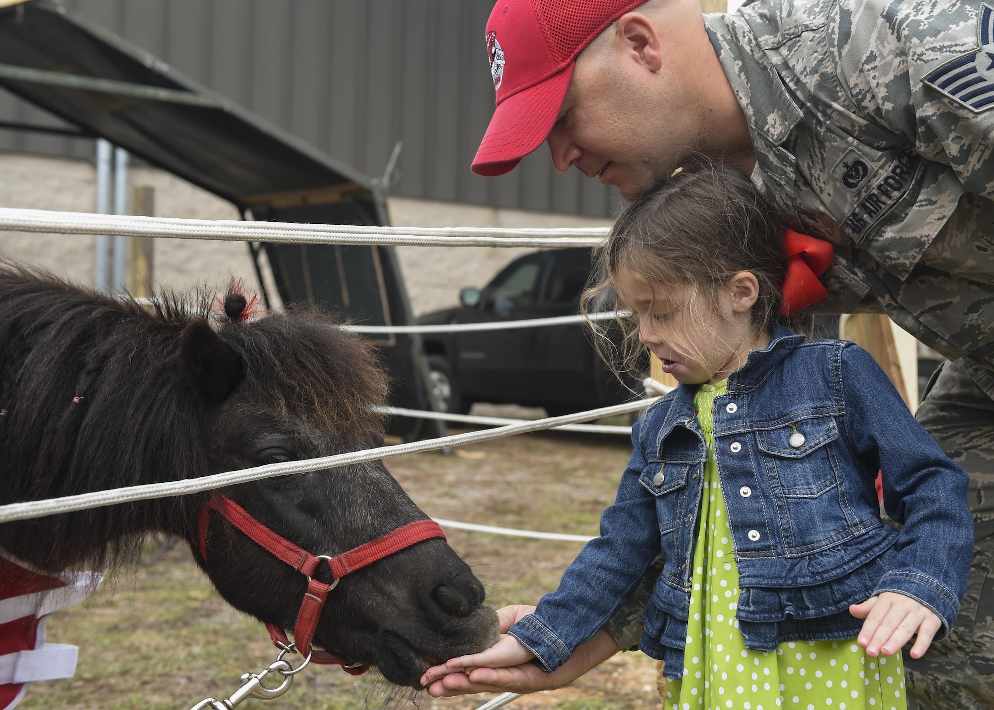 Tech. Sgt. John McAllister, a structure supervisor with the 823rd RED HORSE Squadron, and his daughter, Maggie Grace, feed Charging Charlie at Hurlburt Field, Fla., April 6, 2016. The RED HORSE squadron held an open house at their compound to showcase their mission to family, friends and former RED HORSE members.  (U.S. Air Force photo by Airman 1st Class Kai White)