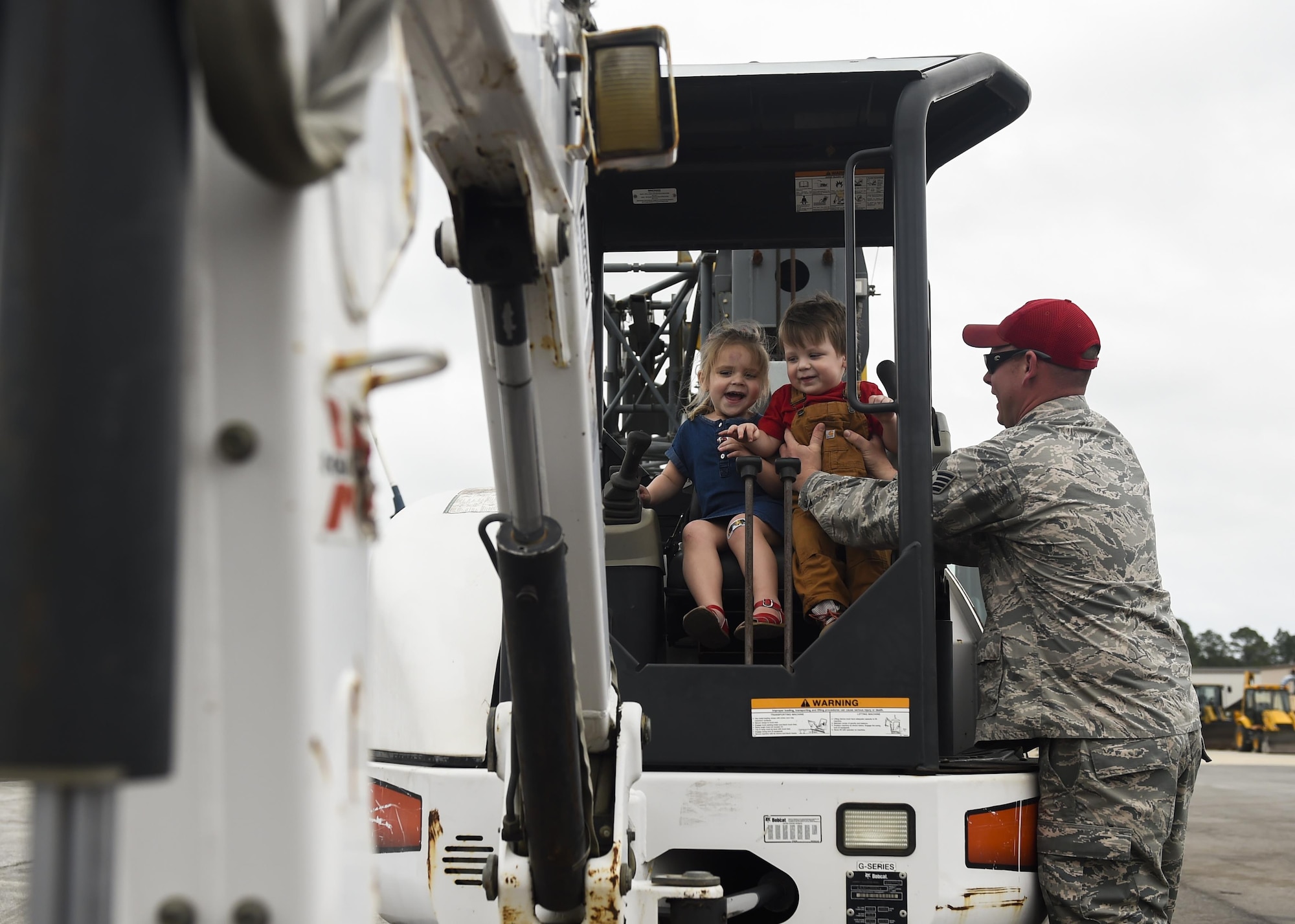 Staff Sgt. Aaron Cutchins, a vehicle mechanic with the 823rd RED HORSE Squadron, shows his children, Addison and Kyler, a piece of equipment that the squadron uses at Hurlburt Field, Fla., April 6, 2016. The RED HORSE squadron held an open house at their compound to showcase their mission to family, friends and former RED HORSE members. (U.S. Air Force photo by Airman 1st Class Kai White)