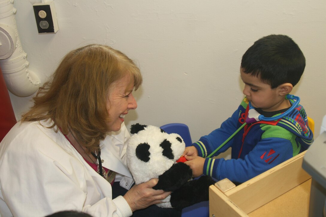 Miguel, 2, listens to his panda’s heartbeat while nurse Marcy Griffo looks on.