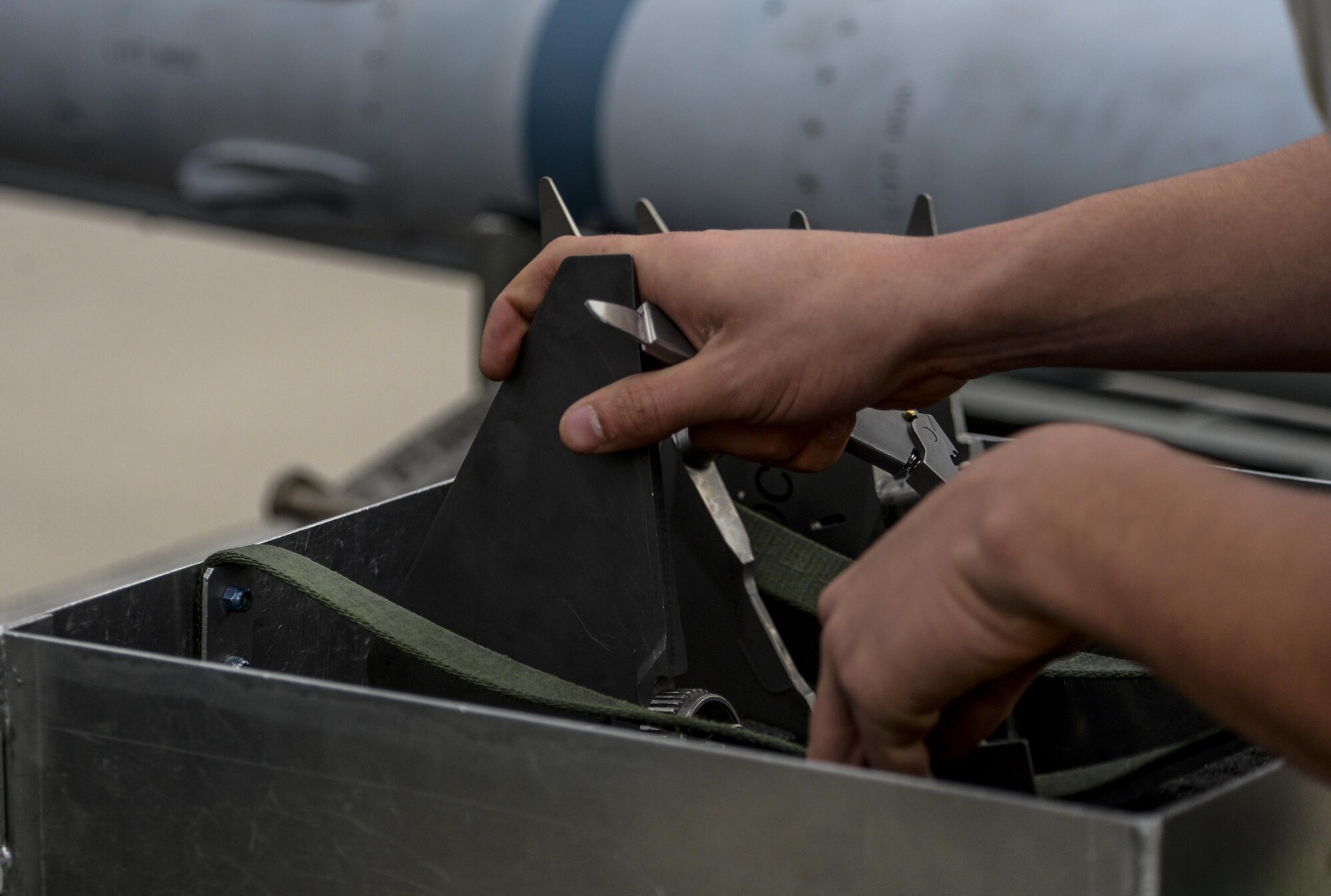 An Airman unhooks the wings of a missile during the 57th Wing Load Crew of the Quarter Competition at Nellis Air Force Base, Nev., April 8, 2016. Crews are inspected on their dress and appearance, orderliness of their tool boxes, the weapons load, and a written test to determine the 57th Maintenance Group’s best weapons load crew of the quarter or year. (U.S. Air Force photo by Airman 1st Class Nathan Byrnes)